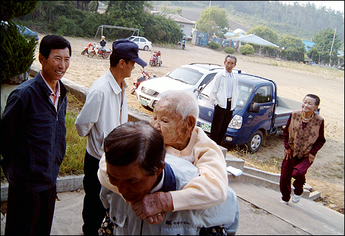 113세 표씨할머니가 조카 한상열씨의 등에 업혀 투표소로 올라가고 있다. 